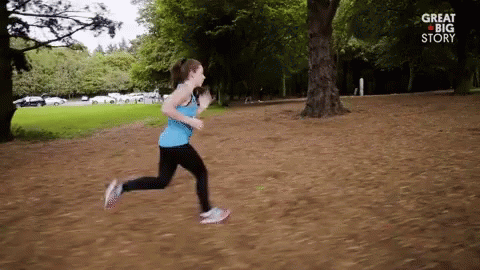 a woman running through the park near a tree