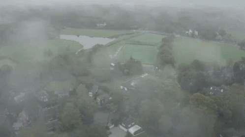 an aerial view of a farm, pasture and village in the fog