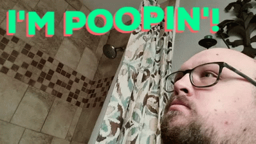 a man with glasses stares into a bathroom with the text i'm in '