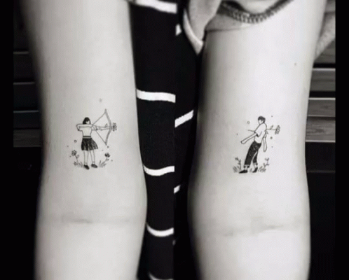 two tattoos on both arms with an arrow and cartoon character