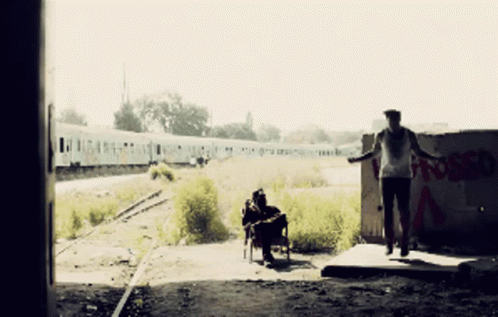 two people are walking in front of some train tracks
