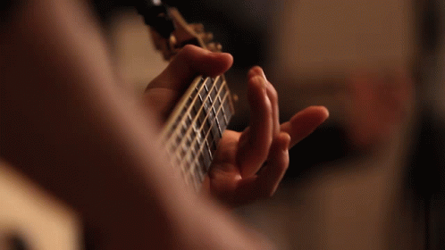 a hand is placed in front of an acoustic guitar