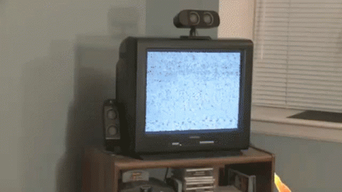 two small speakers with one sitting on top of an old tv