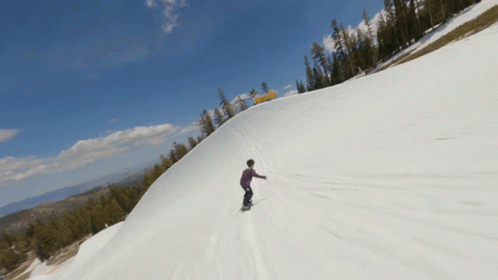 a lone snowboarder traveling down the side of a hill