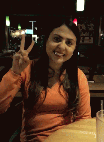a woman is showing the peace sign in front of her