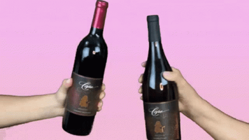 two hands holding wine bottles in one direction