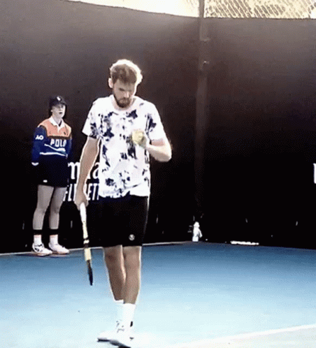 a man in floral shirt and shorts holding a tennis racket on a tennis court