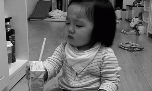 a little girl sitting on the floor in front of an open refrigerator