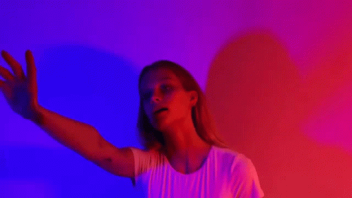 a woman in front of a red wall using her arms to touch the side of her face