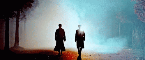 two people walk in the dark in front of smoke and sun