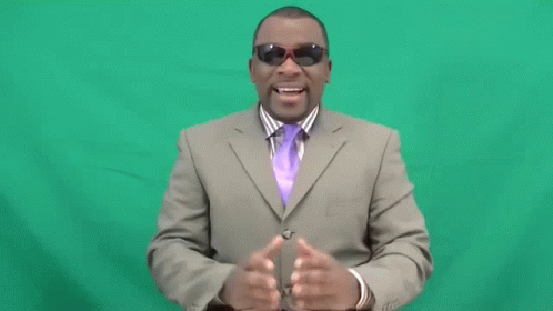 man in suit standing in front of a green screen