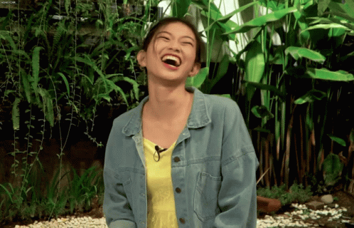 a woman is laughing and standing in a garden