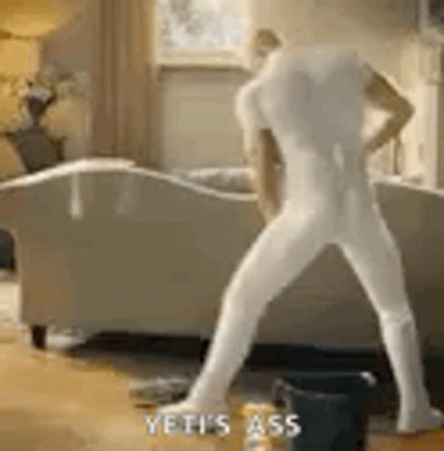 a man in white underwear walking by couch
