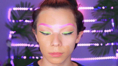 a woman with neon eyeshadows, pink hair and green makeup
