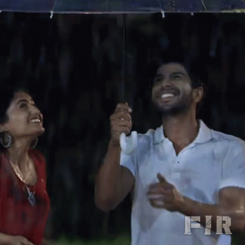 two people standing under an umbrella and laughing