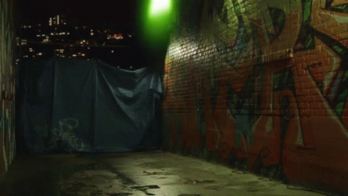graffiti is covering a alley way by lights and a trash can