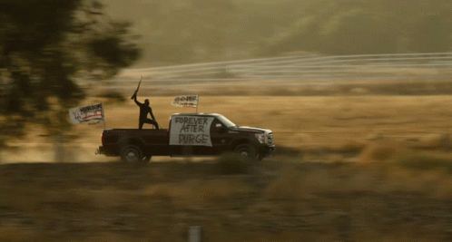 a man standing on top of a truck holding up a sign