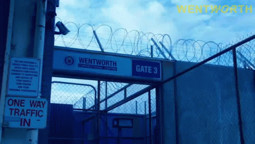 a barbed wire fence that has a gate with signs on it