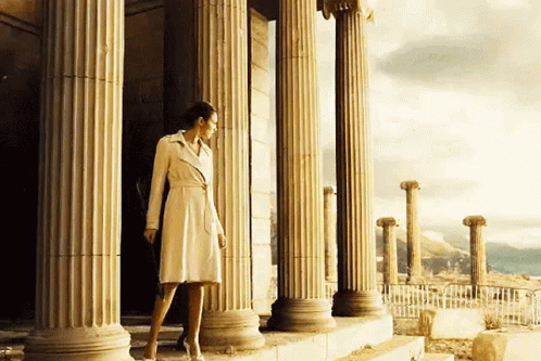 woman in coat standing at large set of pillars