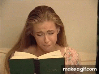 a young lady holding a book in her hand while she reads it