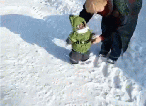 a small boy on snow shoes is helping another person in the snow