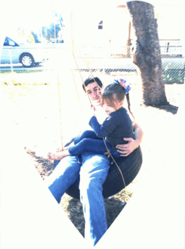 two people sitting on a park bench and holding each other