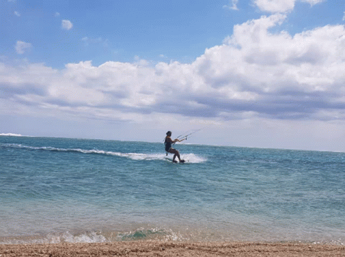 a man riding on top of waves under a cloudy sky