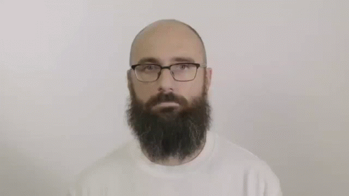 a bearded man with glasses is looking at the camera