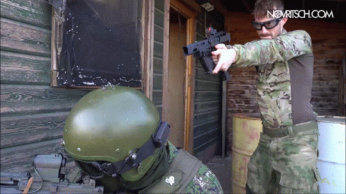 an army uniform is shooting a gun towards another soldier