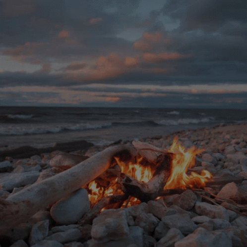 a blue fire is burning next to rocks and water