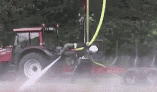 the tractor is being sprayed with water on the road