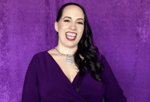 a woman with purple makeup smiling at the camera