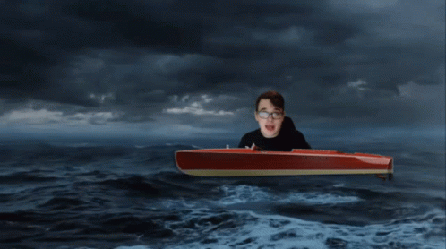 a man in glasses on top of a surfboard in the ocean