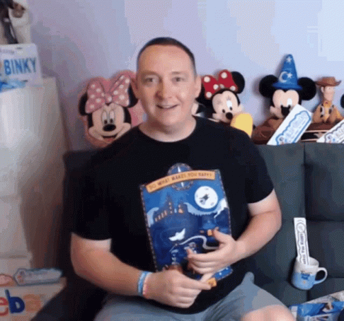 man with mickey mouse and mickey mouse head heads holding a book