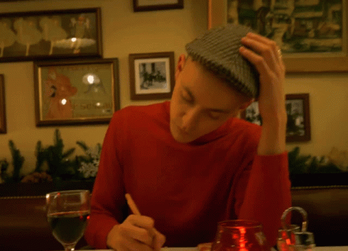 the young man sitting at a table is writing