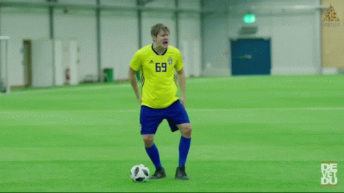 a man in a blue shirt kicking a soccer ball