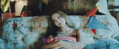 a girl sitting in front of a couch with soing on her lap