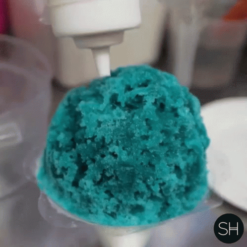 a green cupcake being held by a white plastic scoop
