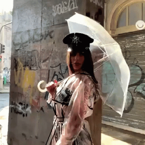 woman with white umbrella on the corner by a wall