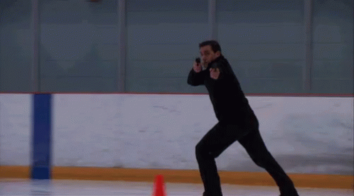 a man in black ice skating on an indoor rink