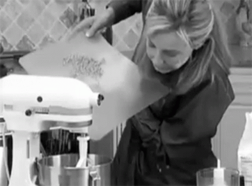a woman is mixing soing in a kitchen