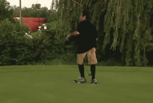man in shorts playing with frisbee on green grass