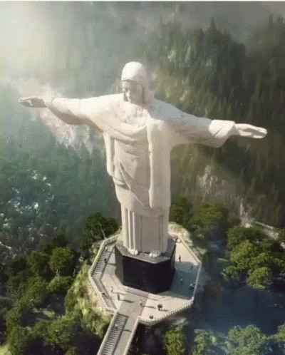 the statue of christ stands in a valley and a path to the mountain