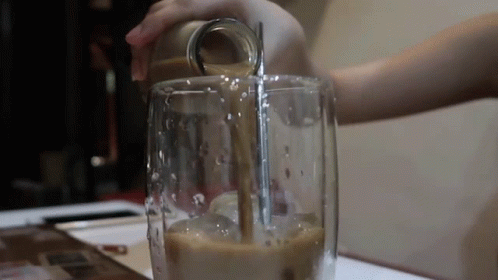 a person with blue hands putting liquid in a blender
