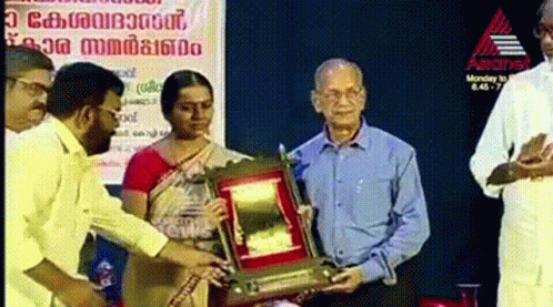 two men and one woman exchanging an award at the event