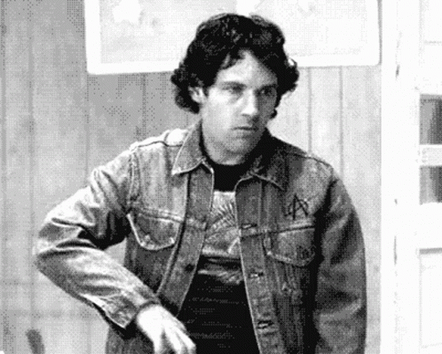 a man wearing a jean jacket holding a knife