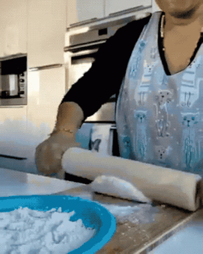 a woman rolling some dough in a kitchen