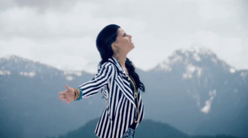 the woman is dressed in striped clothing on top of a mountain