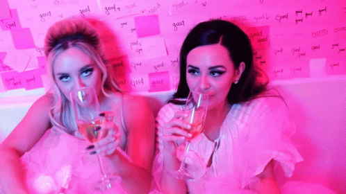 two female in white dresses with drinks in their mouths