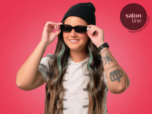 a woman in sunglasses and beanie looking through her hair